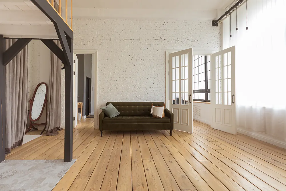 Wide-plank hardwood floor in an open living space with exposed brick